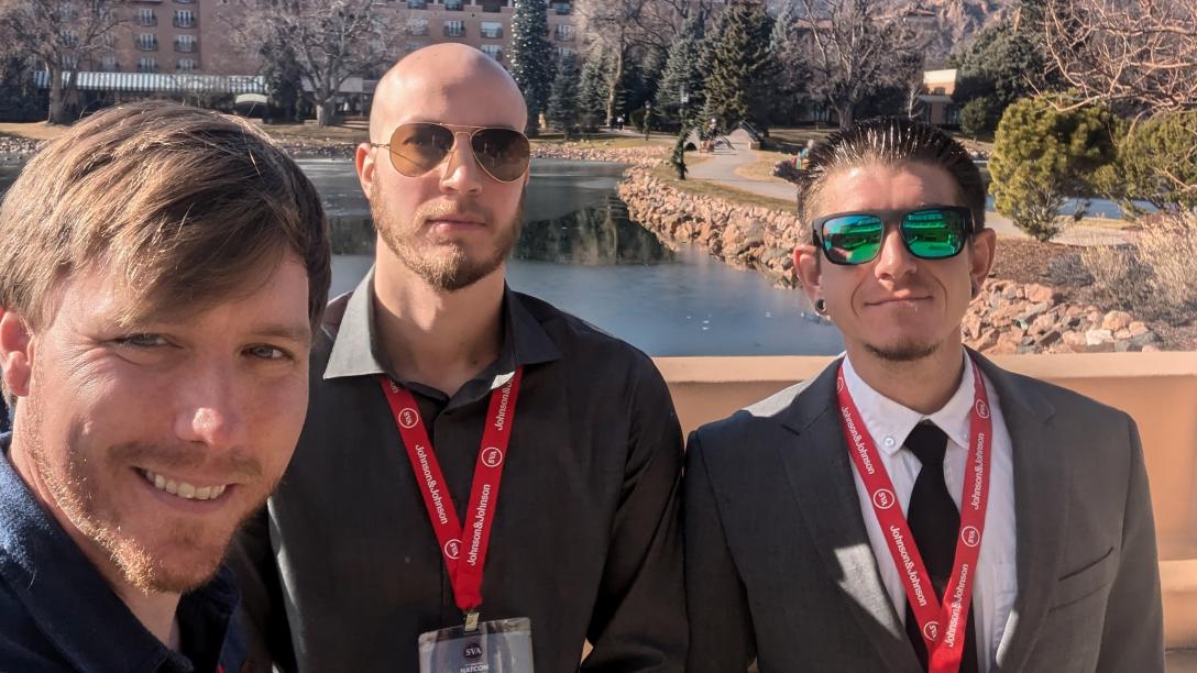 3 men outdoors wearing red lanyards