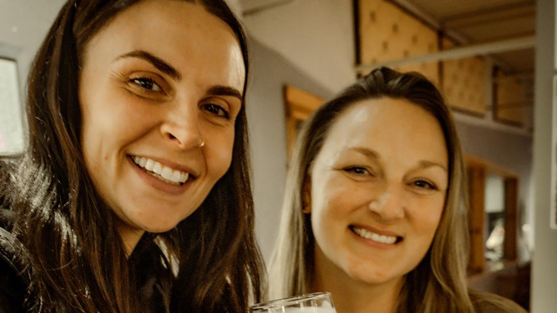 Close up of two women standing next to each other smiling at the camera