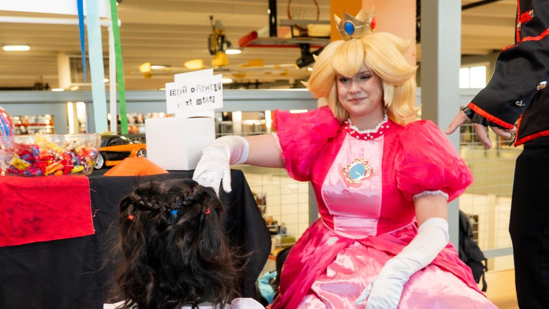 A person dressed as Princess Peach kneels smiling at a child in a princess dress.