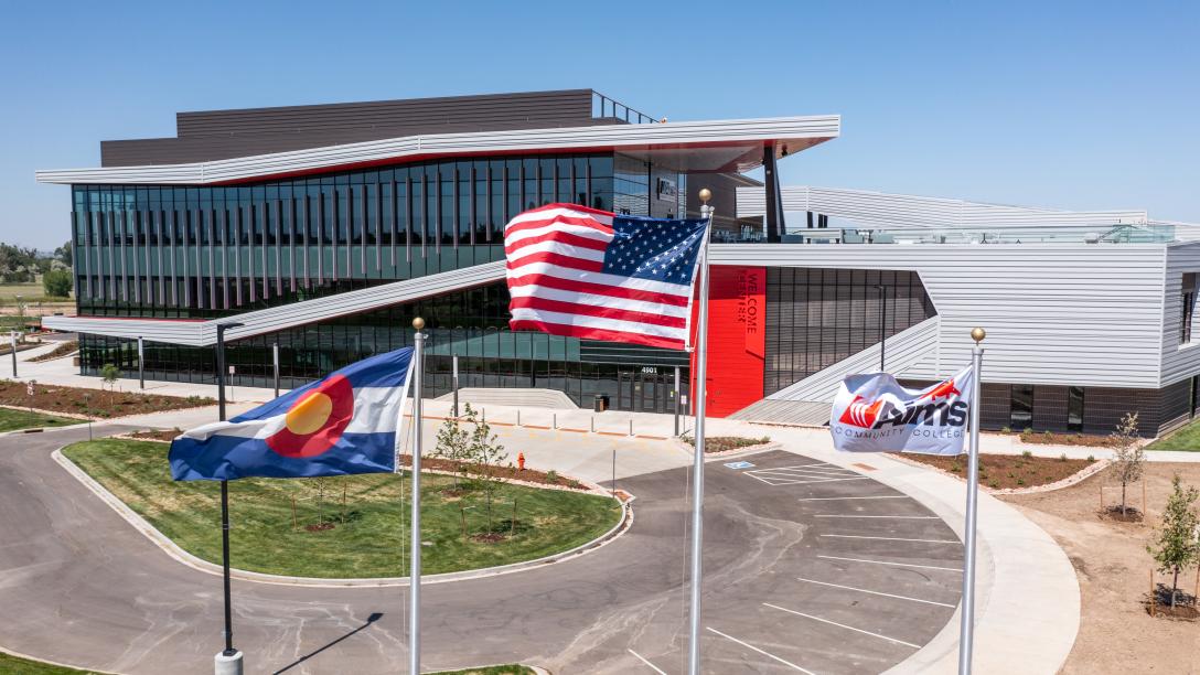 The Colorado, United States and Aims Community College flags fly in front of the Welcome Center