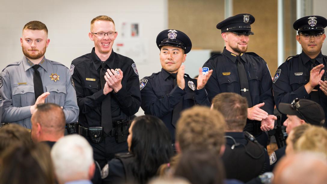 Aims Peace Officer Academy cadets in uniform applauding during a graduation ceremony