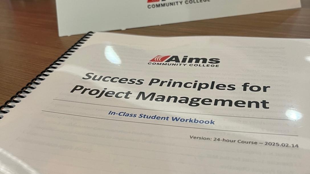 White workbook with black spiral binding titled "Success Principles for Project Management"