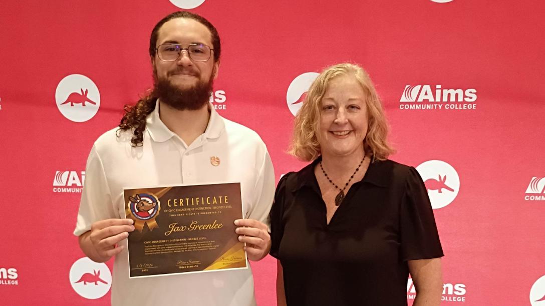 Student holding a certificate for earning the Bronze Civic Engagement Distinction and standing next to a member of the Civic Engagement Council.