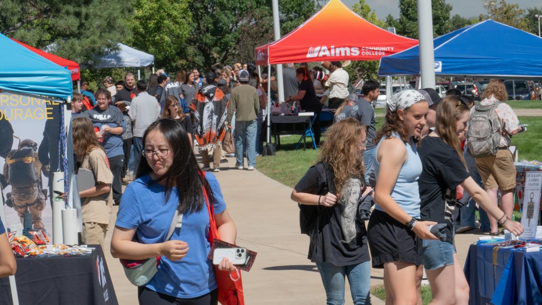 Students visiting department booths covered by colorful tents at the 2026 annual Greeley Fall In.