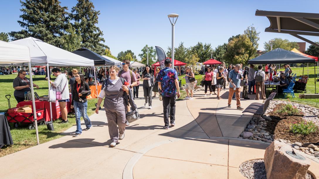 Students wandering between department tables covered by colorful tents at the 2026 annual Greeley Fall In.