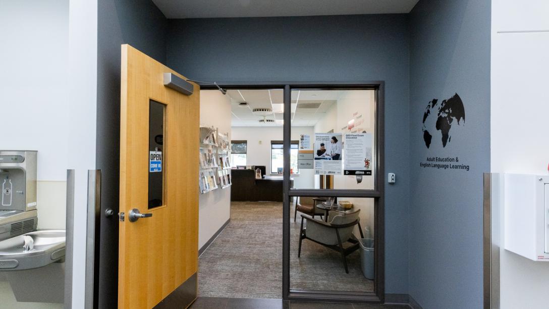 Entryway to Summit Building offices with a gray wall, leading through a wooden door