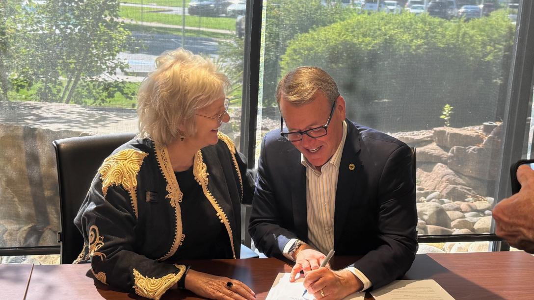 Dr. Leah L. Bornstein and Dr. Andy Feinstein signing agreement at desk