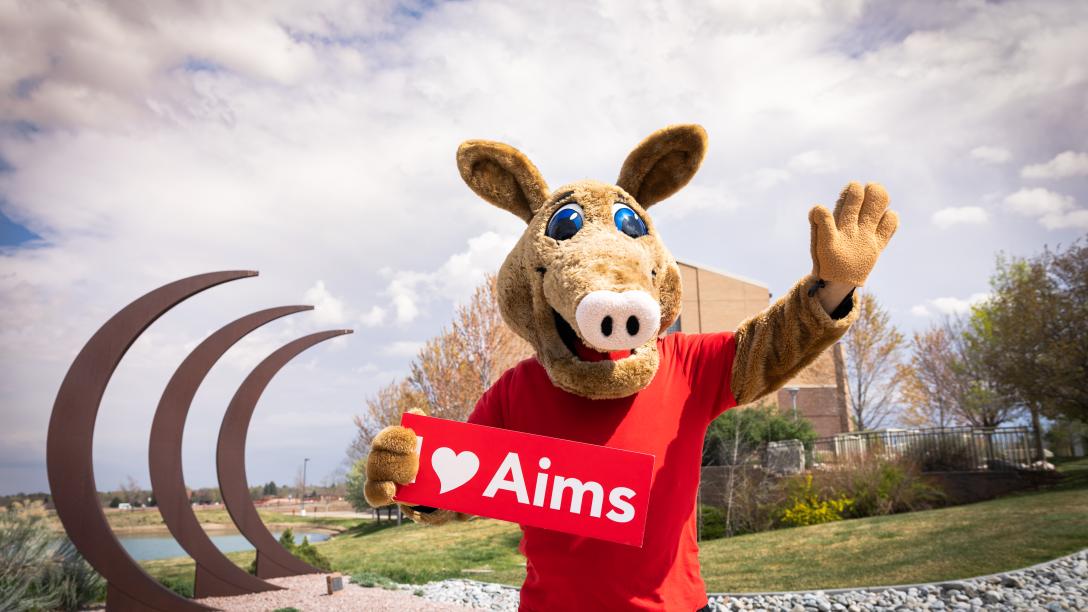 Arty the Aardvark Mascot at the Aims Greeley campus holding a sight that says I love Aims