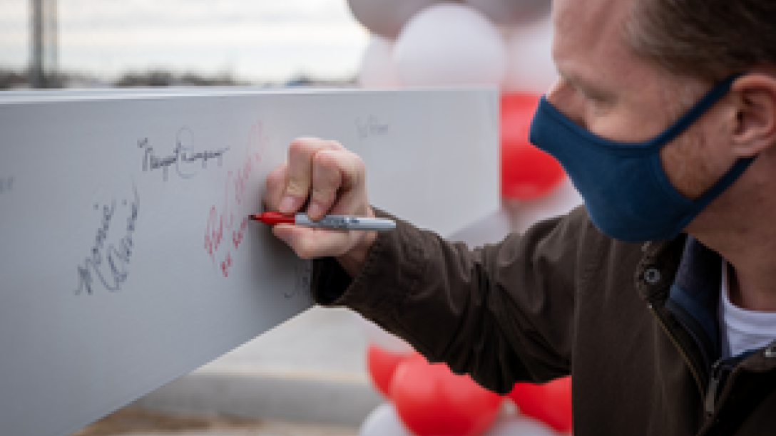 Masked person signing beam