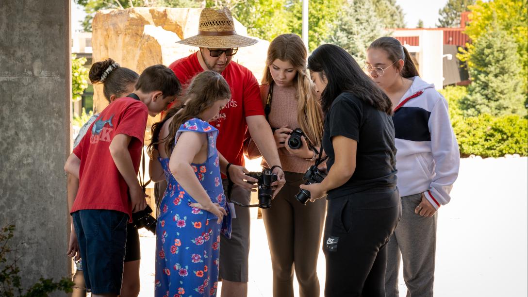 Students and teacher huddled around a camera in photography class