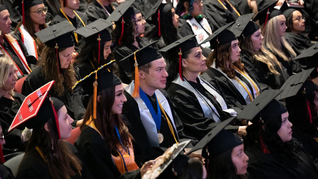 Graduating students wearing caps and gowns seated in Welcome Center Auditorium during Spring 2022 Commencement