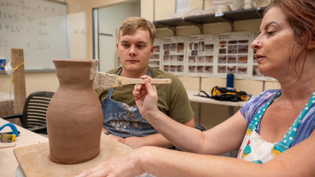 Woman painting pottery project with man watching