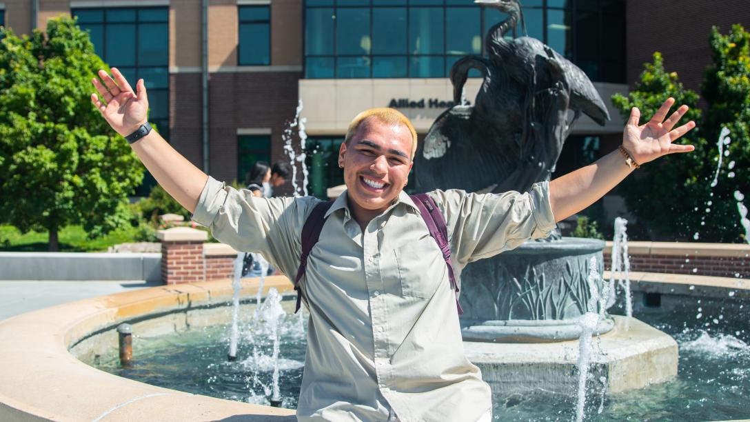 Student at in front of a fountain on Greeley Campus
