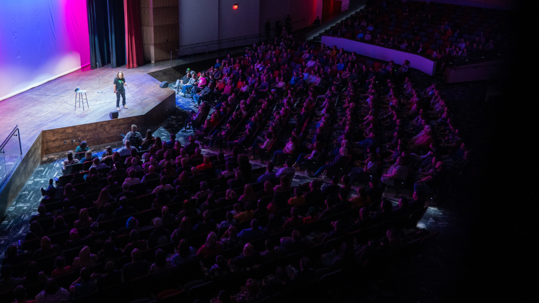 Comedian Josh Blue performing in front of a packed audience at the Aims Welcome Center.