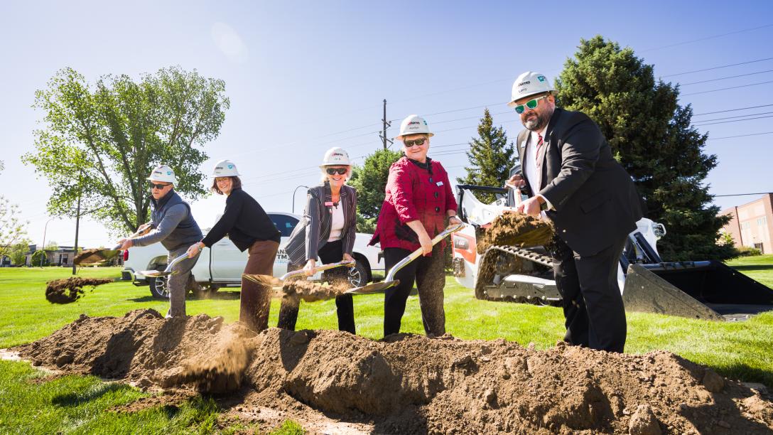 Five people digging dirt at groundbraking ceremony