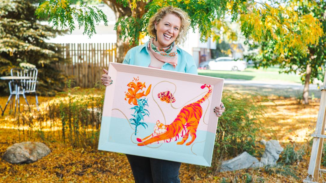 Aims alumna Mel Calderon holding one of her paintings