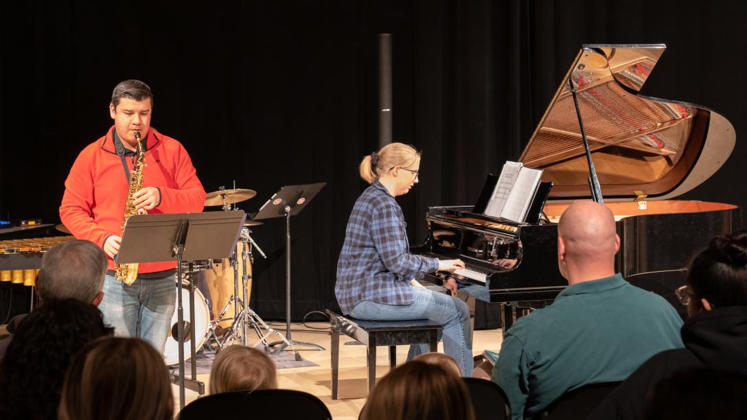 Aims students playing saxophone and piano on stage