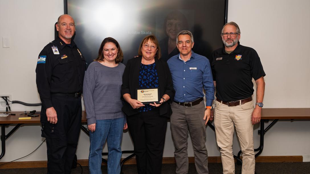 five people standing with award