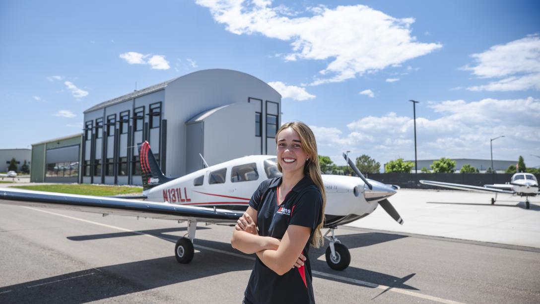 Samantha Walsh with plane and Aims Flight Training Center in the background