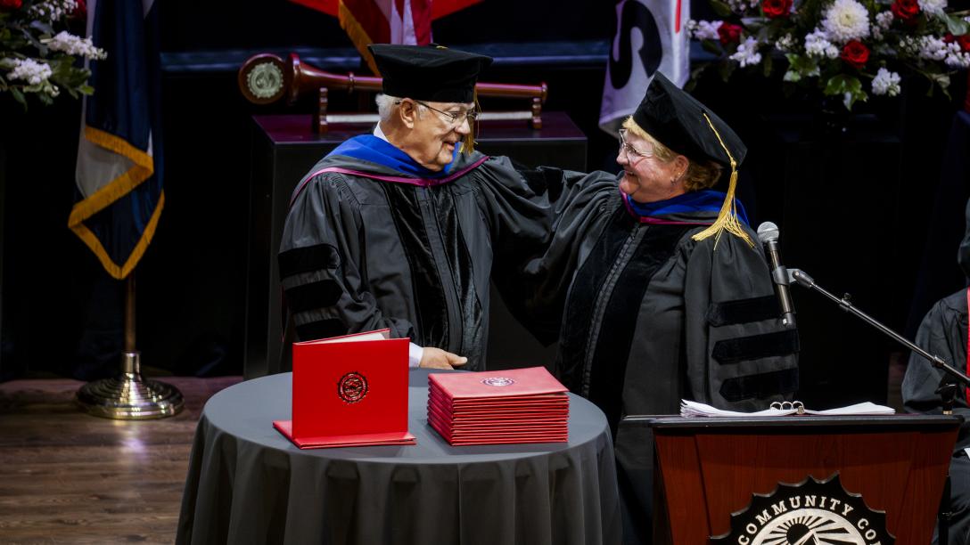 Lyle Achziger and Marilyn Schock, Chair of the Aims Board of Trustees on the Commencement Stage