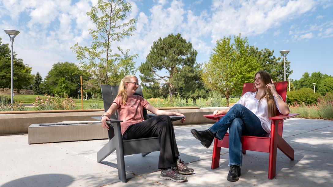Two students sitting outside on the Aims Student Commons courtyard