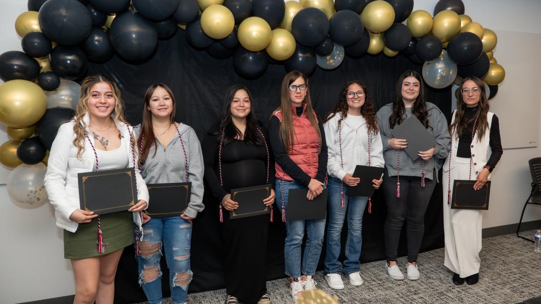students standing with awards against balloon backdrop