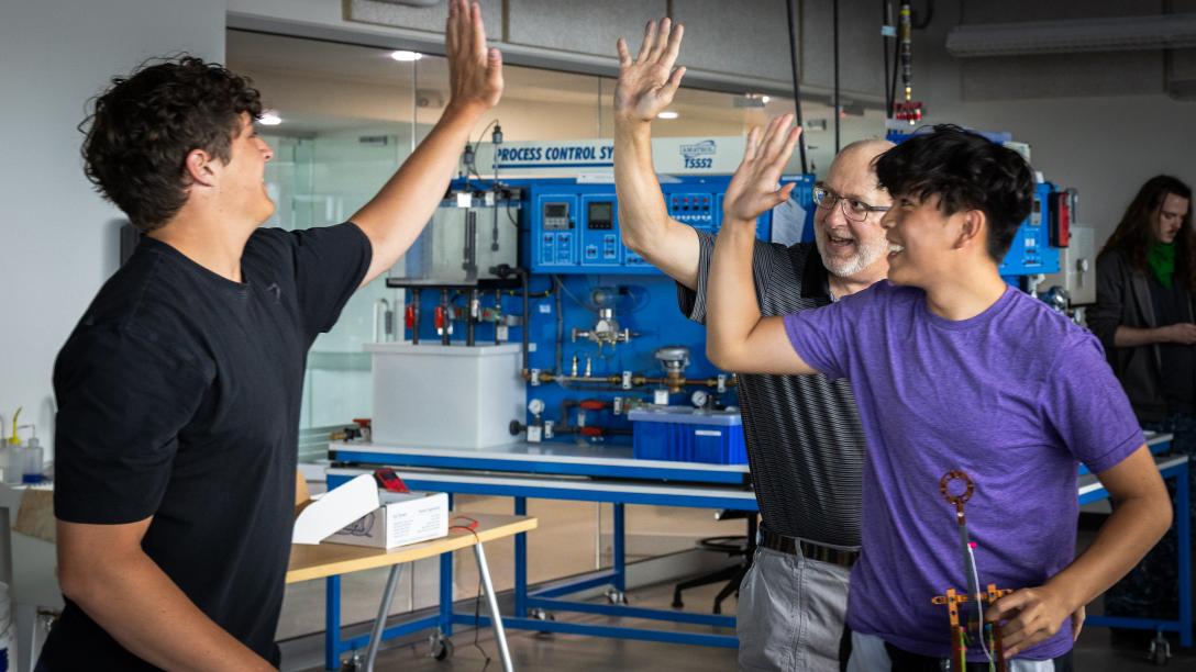 teacher and two students high fiving each other