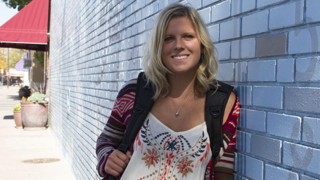 Woman with backpack leaning against wall