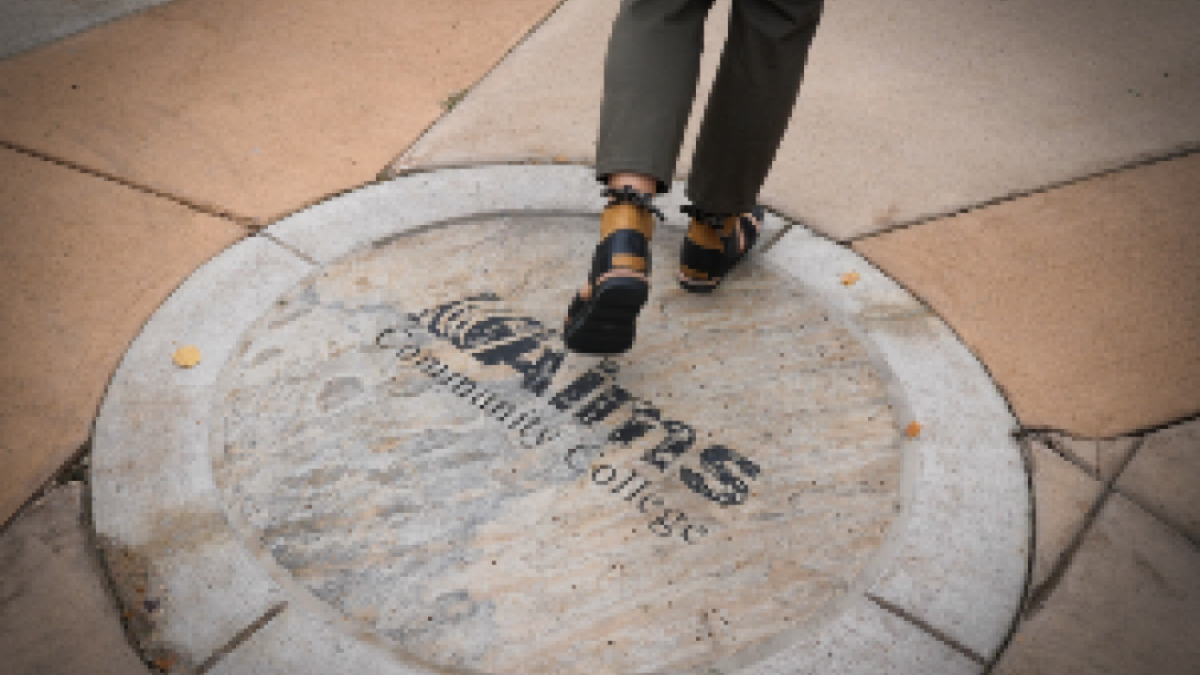 Person walking over Aims sidewalk logo