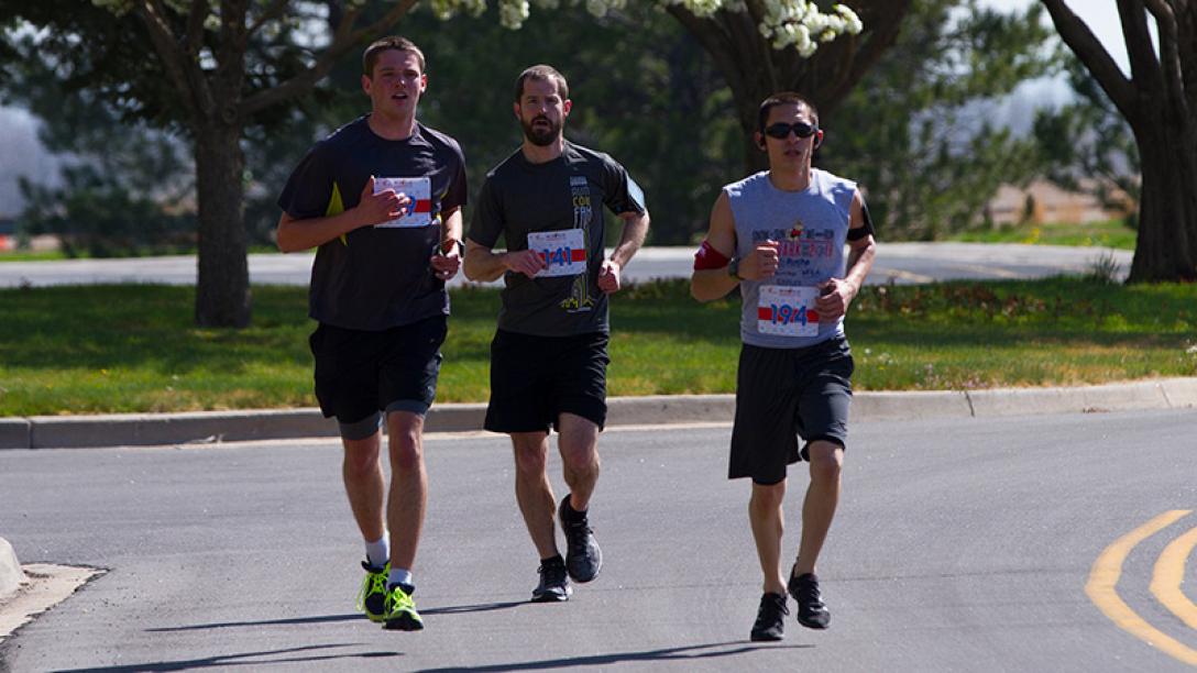 Three men running in street