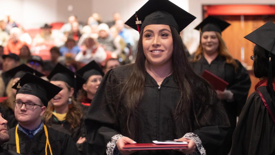 Graduating student and other graduatutes during commencement at Aims