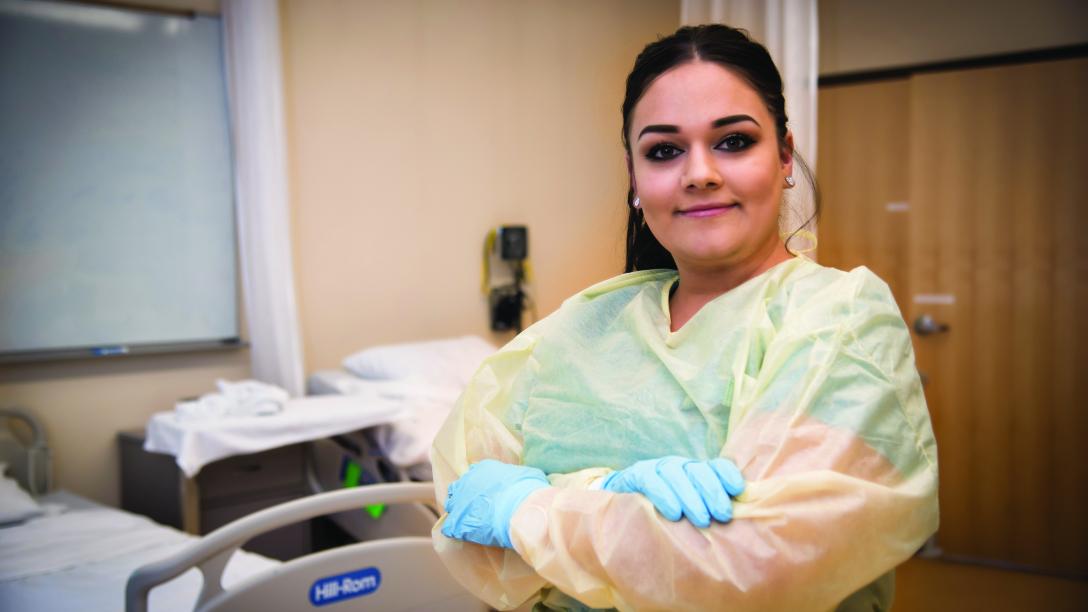 Aims CNA student in hosptial room with rubber gloves