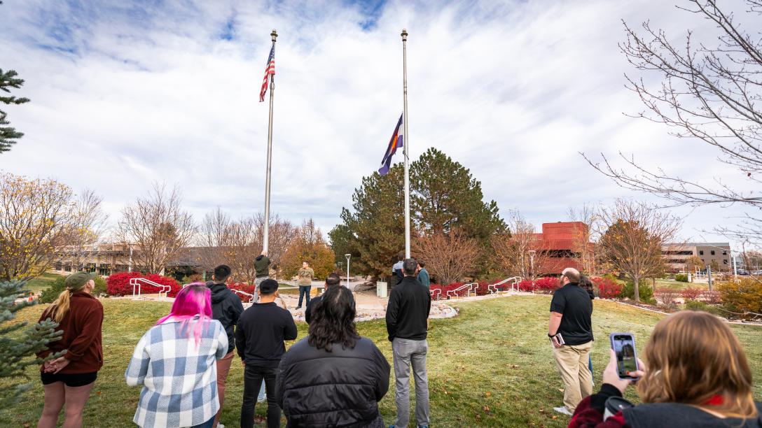 People watching a USA and Colorado Flag being raised