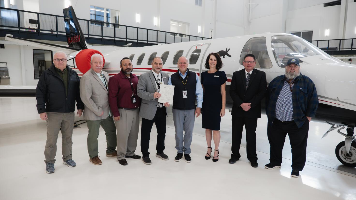 Group infront of airplane in hanger
