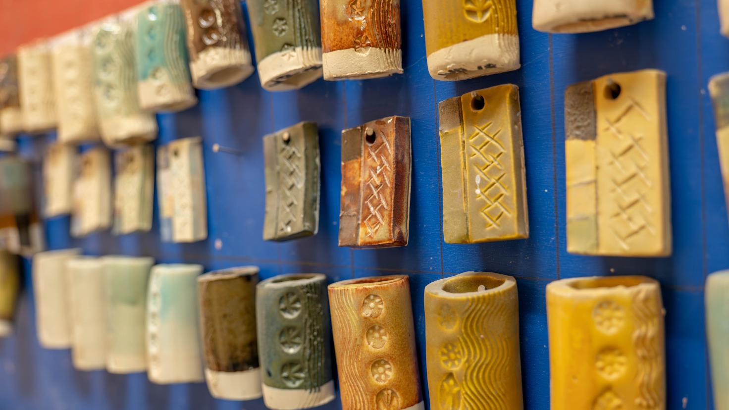 ceramic tiles with earth tone colored glazes hanging on blue wall