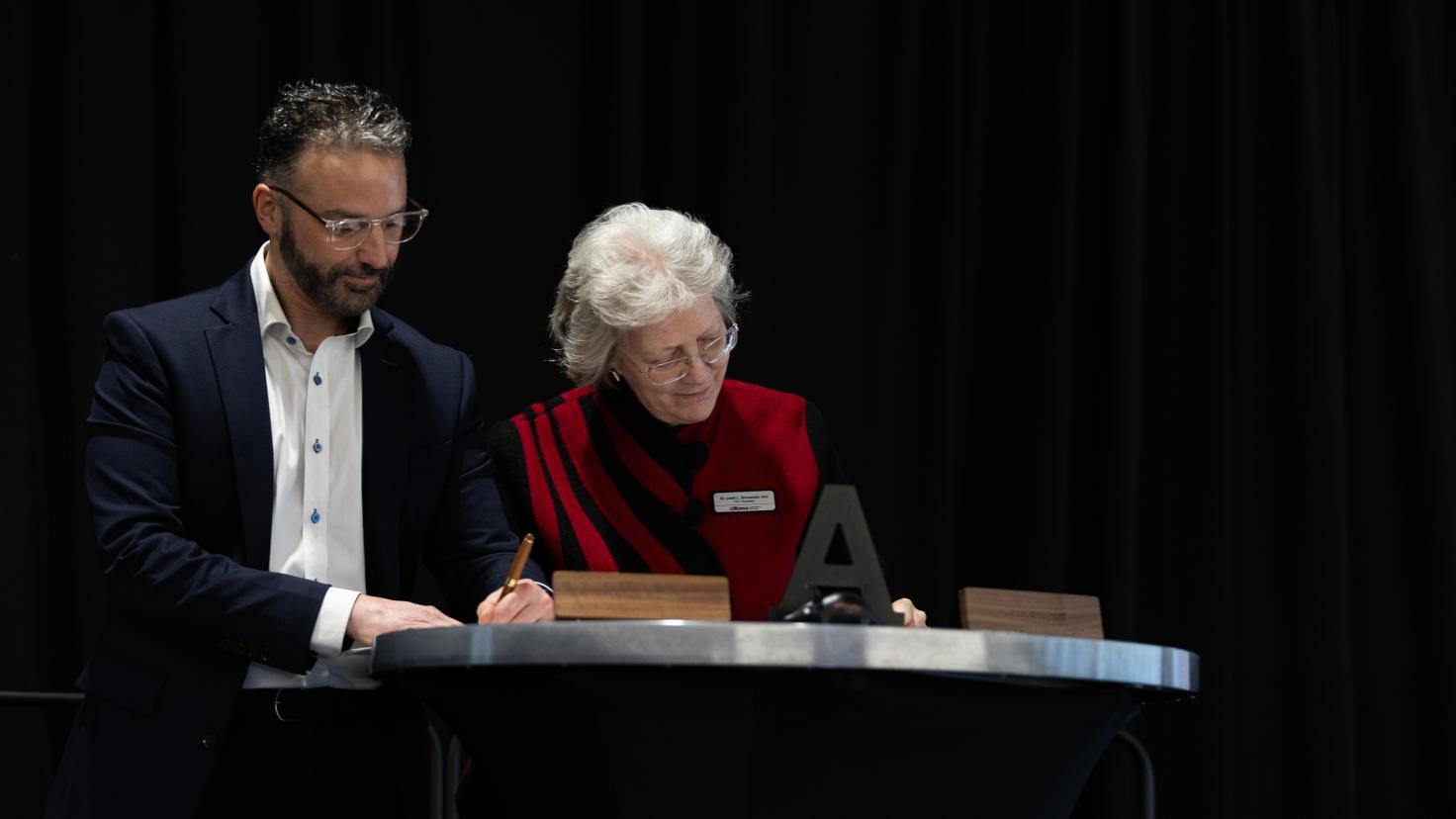 Zach and Dr. B signing agreement on stage