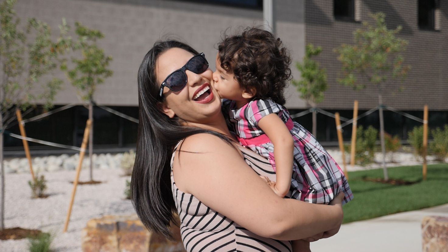 smiling woman holding toddler who is kissing her cheek