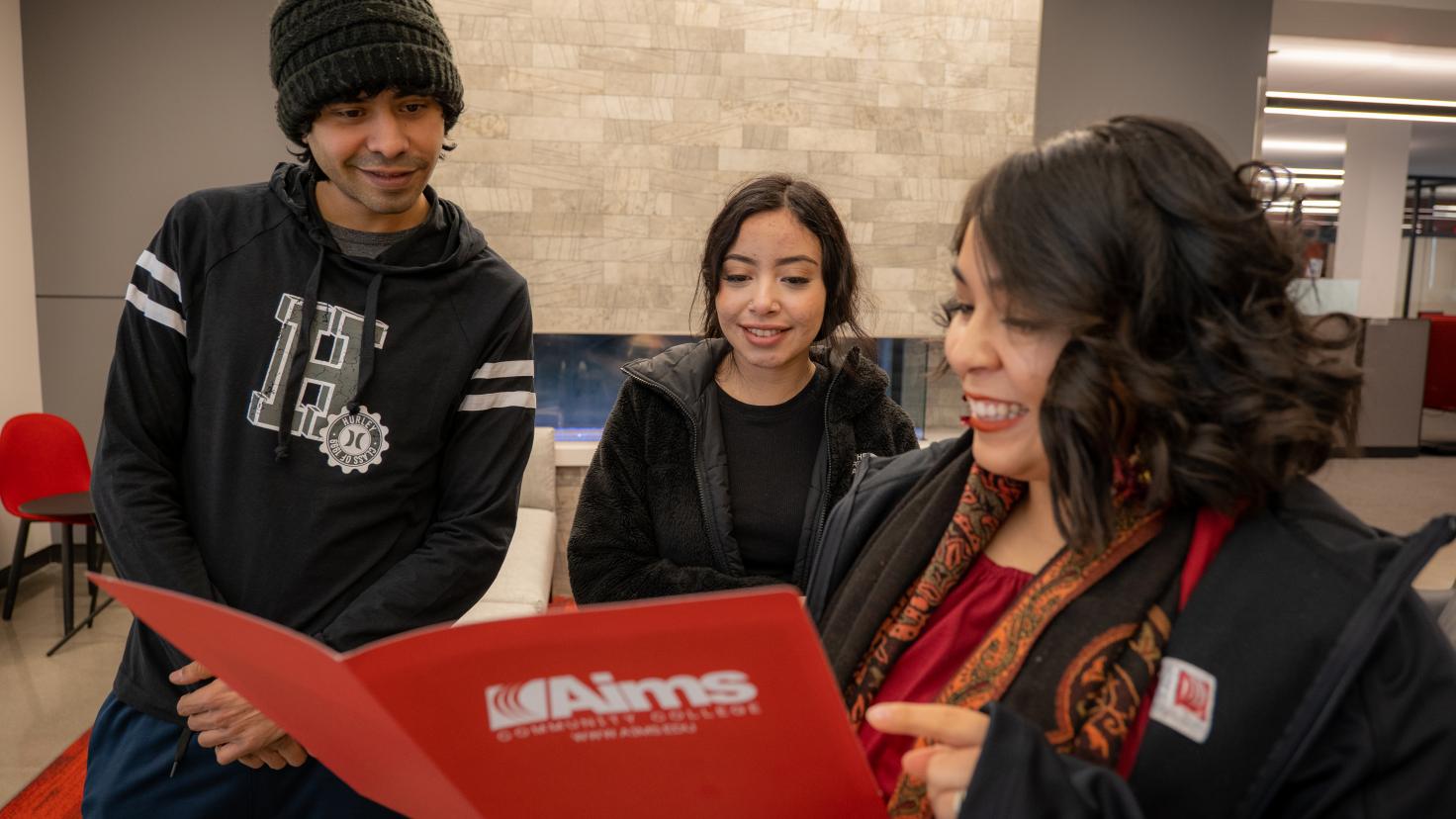 aims student with advisor looking over folder of enrollment materials