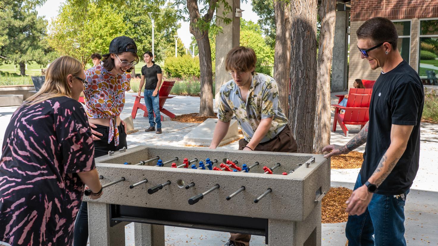 Aims students playing foosball and cornhole in the courtyard