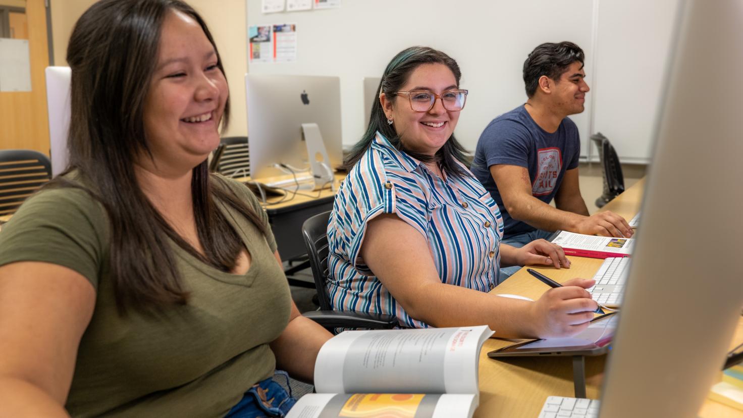 Three Aims students working at a computer lab desk.