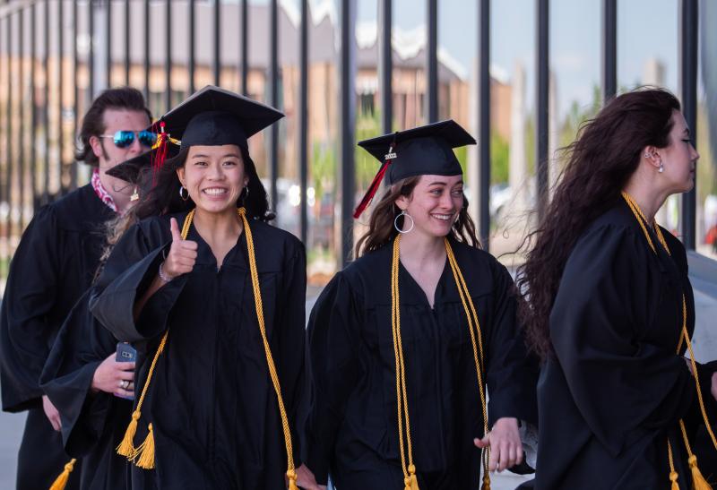 An Aims graduate making a thumbs up gesture during a commencement ceremony