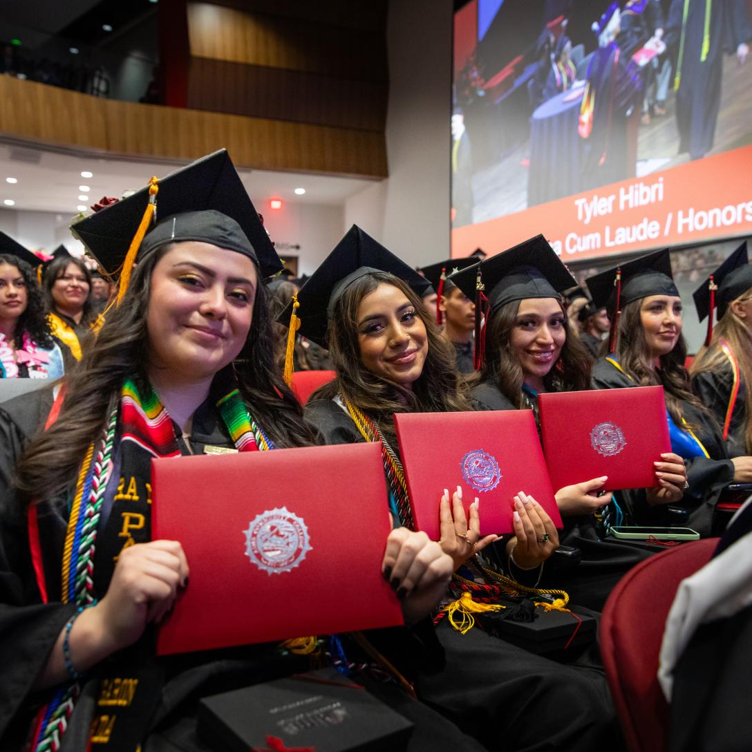 row of aims graduations holding their diplomas