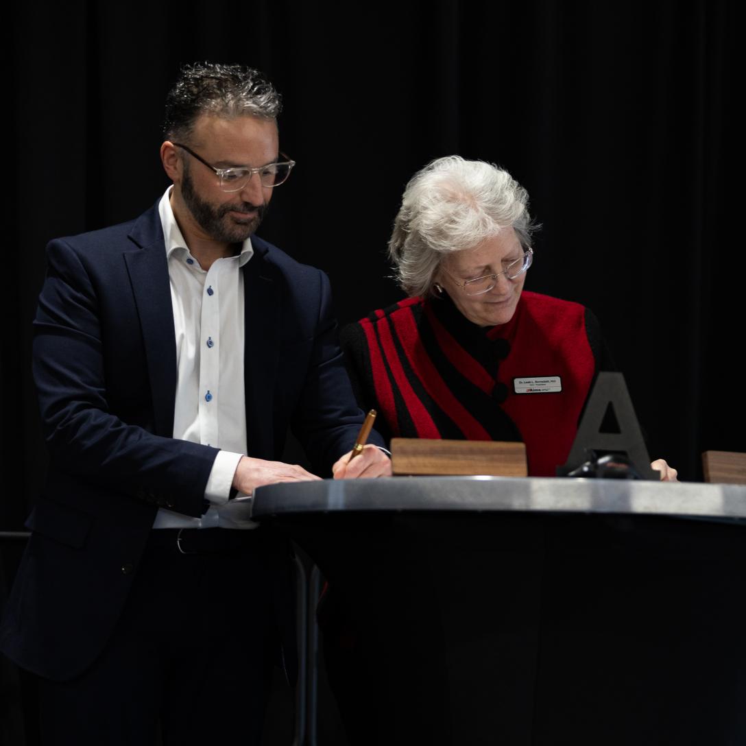 Zach and Dr. B signing agreement on stage