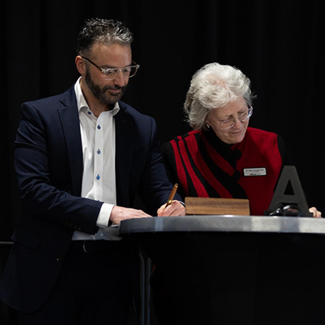 Zach and Dr. B signing agreement on stage