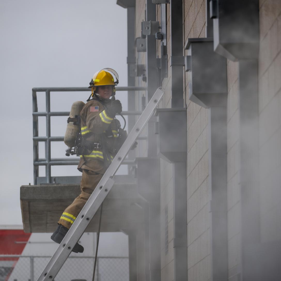 Tobi Howell climbing a ladder at the Sim City on the Aims Windsor Campus