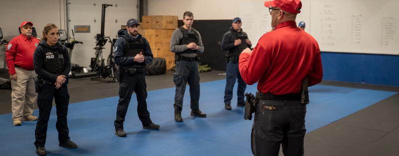 Aims police academy cadets in tactical gear during a training session