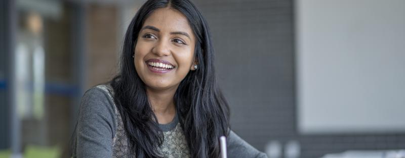 A smiling student smiles while doing coursework