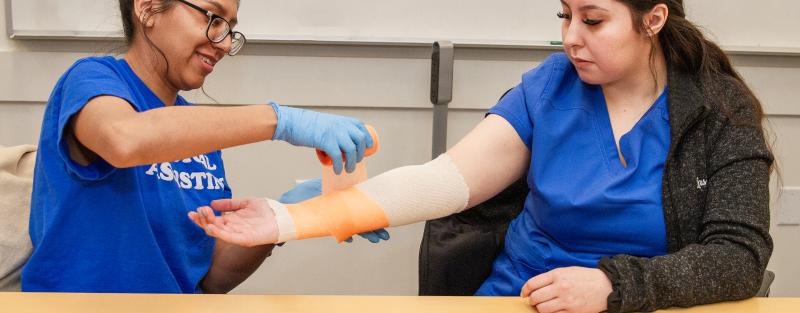 Aims Medical Assistant Certificate students practicing bandaging a wound in a lab setting