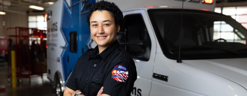 Aims EMT student Tatum Gipson posing in uniform in front of an ambulance