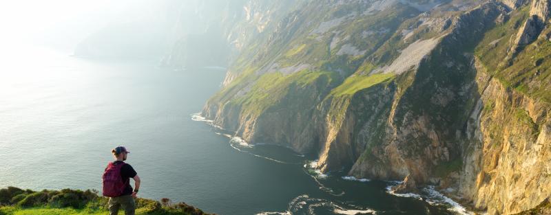 A backpacker looks out over the cliffs in Donegal, Ireland